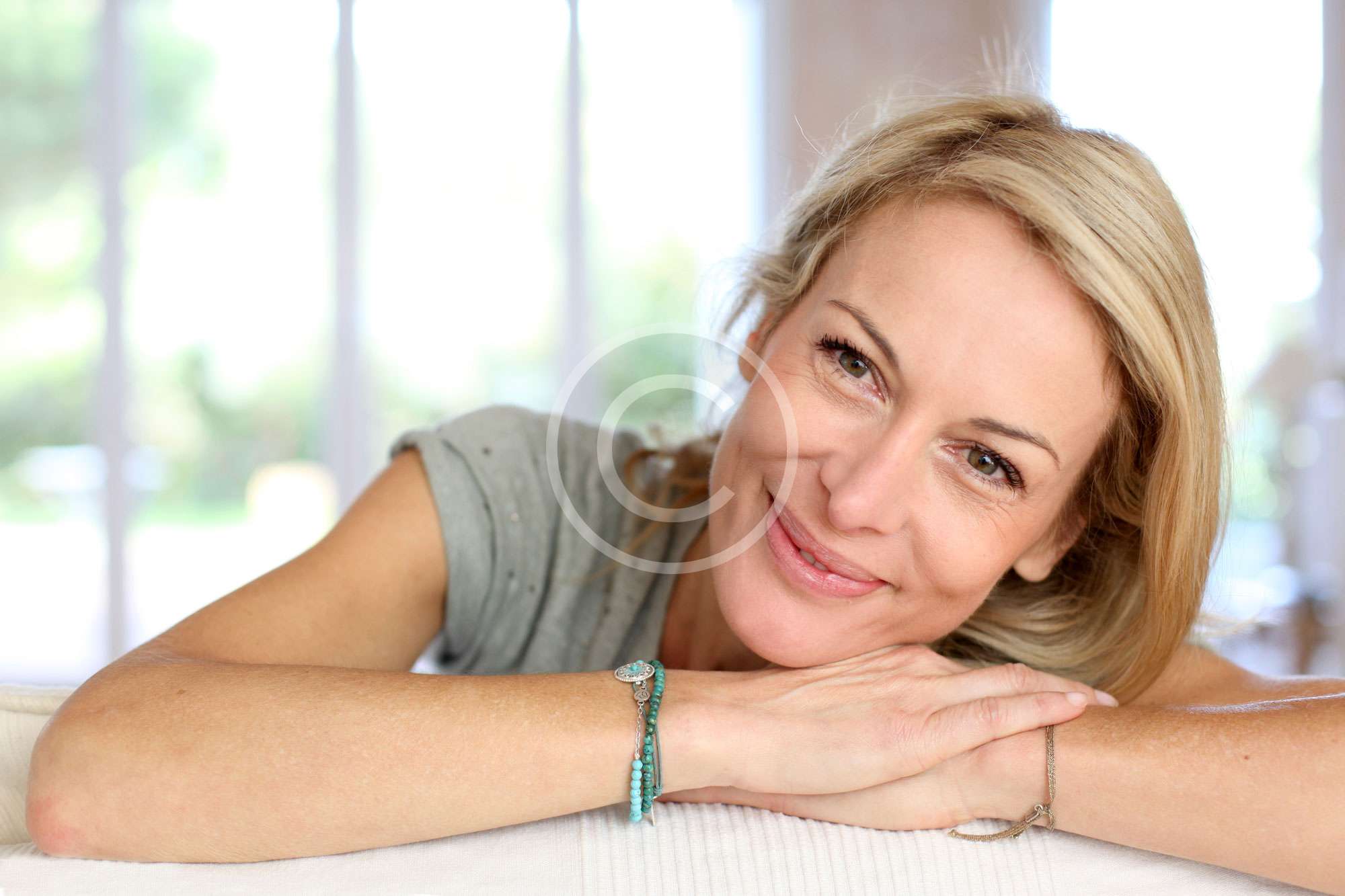 donna bionda di bolzano sorride felice senza stress mentre appoggia la testa sulle mani e guarda la fotocamera